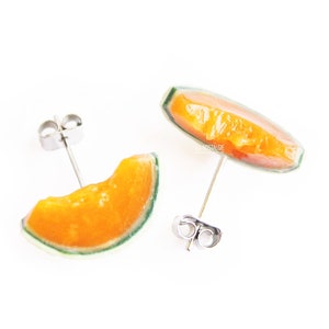 Peut inclure: Une paire de boucles d'oreilles en forme de tranche de melon cantaloup. Les boucles d'oreilles sont en résine transparente et ont un fermoir argenté.