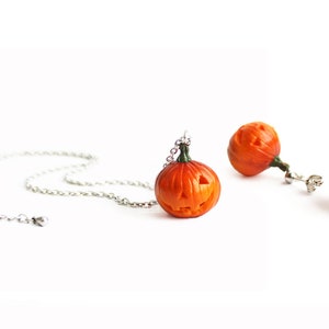 May include: A set of Halloween jewelry featuring orange pumpkin earrings and a necklace with a pumpkin pendant. The pumpkins have carved faces and are made of polymer clay.