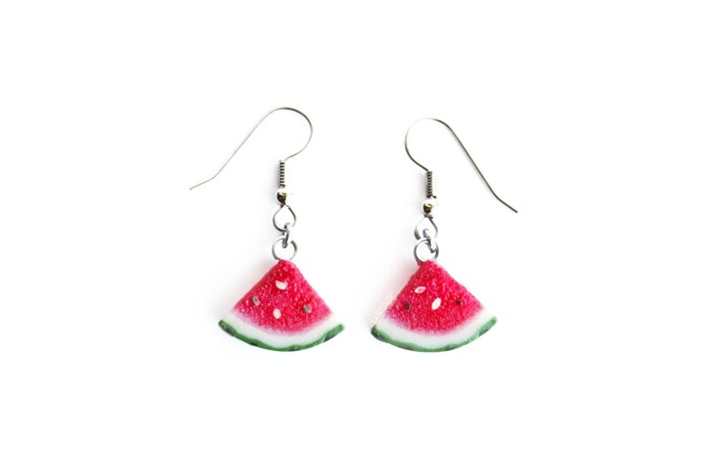May include: A pair of silver dangle earrings with watermelon slice charms. The watermelon slices are red with black seeds and a green rind.