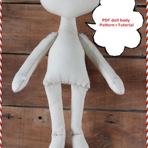 May include: A handmade, off-white doll body with a rounded head, long arms, and legs. The doll's body is made of soft fabric and has stitched details. A speech bubble with the text "PDF doll body Pattern+Tutorial" is visible.