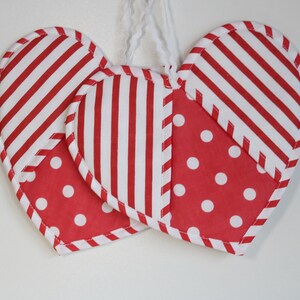 May include: Two red and white striped fabric hearts with white polka dots. The hearts are sewn together and have a white string attached to the top.