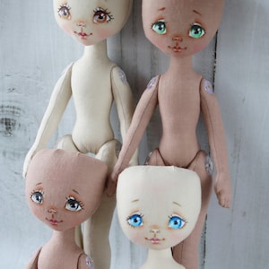 May include: Four handmade cloth dolls with painted faces and button joints. The dolls are in various skin tones and have different colored eyes.