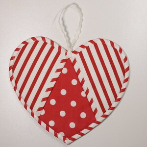 May include: A red and white striped heart-shaped ornament with a red and white polka dot center. The ornament has a white loop for hanging.
