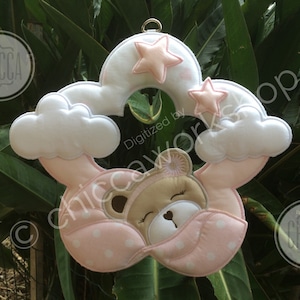 Peut inclure: Mobile pour bébé avec un ours endormi niché dans un nuage et un arc-en-ciel roses et blancs. Le mobile comprend un ours endormi, des nuages et des étoiles. Le mobile est conçu avec une palette de couleurs pastel douces.
