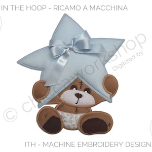 May include: An adorable machine embroidery design featuring a brown teddy bear holding a light blue star with a bow. The design includes the text "IN THE HOOP - RICAMO A MACCHINA" and file size options. The bear wears a diaper with a floral pattern.