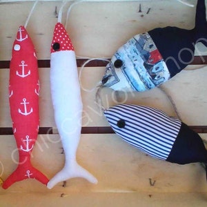 Può includere: Cinque giocattoli di pesce in tessuto fatti a mano. I pesci sono di vari colori e motivi, tra cui rosso, bianco, blu e giallo. I pesci sono lunghi circa 30 cm.