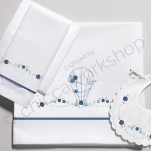 Peut inclure: Un ensemble de literie pour bébé en blanc brodé avec un ballon à air chaud bleu et un motif floral. L'ensemble comprend un drap-housse, un drap plat et une bavette.