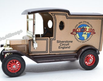 May include: A die-cast model of a vintage delivery truck. The truck is brown with black trim and red wheels. The side of the truck features the text "MOTOR 100" and "Silverstone Circuit England".