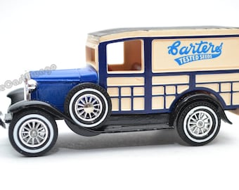 May include: A blue and cream toy model of a vintage Ford delivery truck with a wooden panel body. The truck has the words "Barters Tested Seeds" printed on the side.