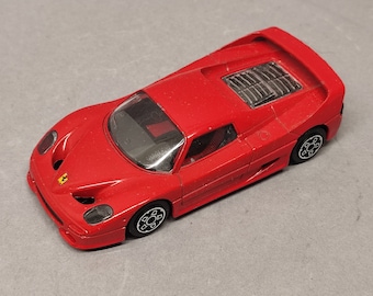 Può includere: Un'auto giocattolo rossa modello Ferrari F50, una classica auto sportiva italiana. L'auto ha ruote nere e un interno dettagliato.