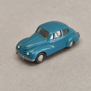 Puede incluir: Un modelo de coche de juguete azul turquesa con un parachoques delantero plateado y ruedas negras.