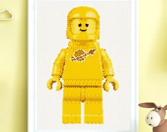 May include: A yellow Lego minifigure wearing a space helmet and a yellow spacesuit with a brown patch on the chest. The minifigure is smiling.
