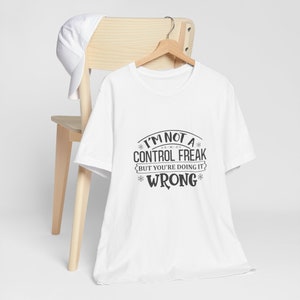 May include: White t-shirt with a black graphic that says "I'm not a control freak but you're doing it wrong".