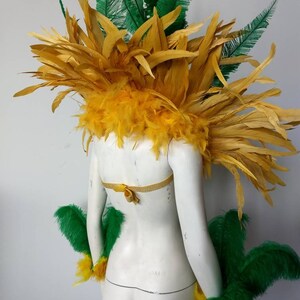 May include: A yellow and green feather costume with a yellow feather headpiece and green feather arm cuffs.