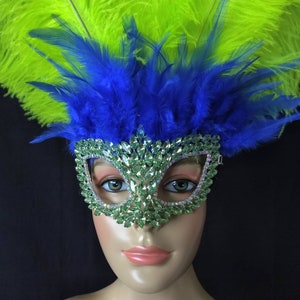 Pode incluir: Uma m&aacute;scara de carnaval verde e prateada com pedrarias, decorada com penas azuis e verdes.