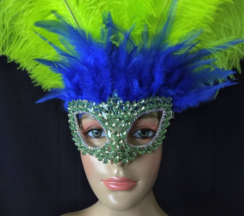 Pode incluir: Uma m&aacute;scara de carnaval verde e prateada com pedrarias, decorada com penas azuis e verdes.