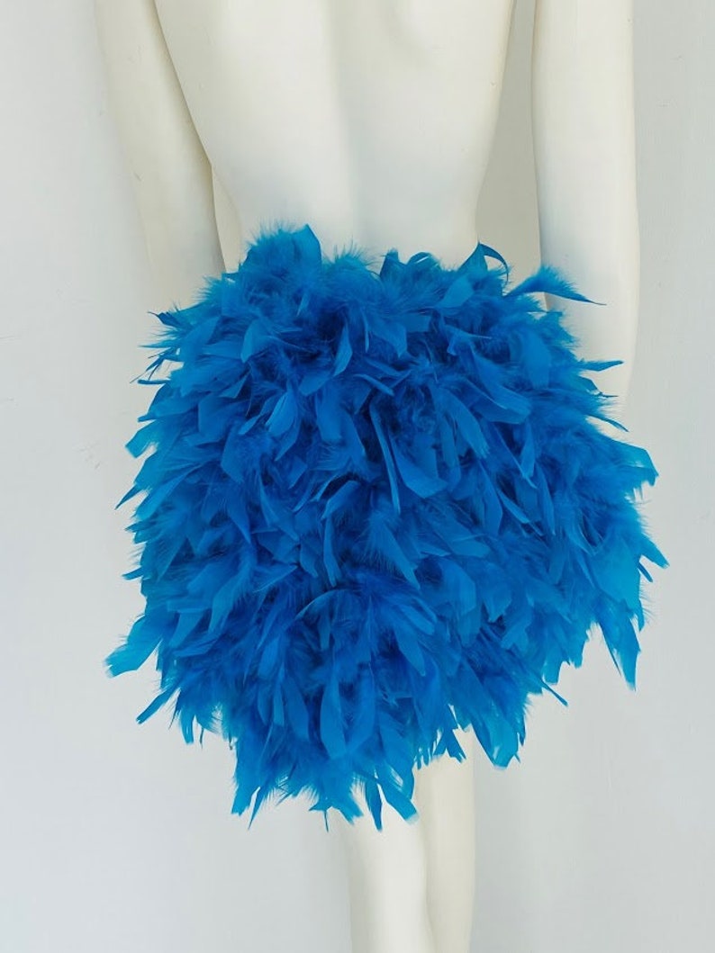 Puede incluir: Una falda de plumas azul esponjosa. La falda est&aacute; hecha de muchas plumas que se juntan para crear un look completo y voluminoso.