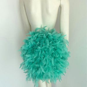 Puede incluir: Una falda de plumas turquesa. La falda est&aacute; hecha de un material suave y esponjoso, perfecta para un disfraz o una fiesta.