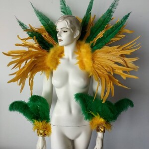 May include: A yellow and green feather costume shoulder piece and matching arm cuffs. The shoulder piece is large and dramatic, with feathers radiating out from the center. The arm cuffs are smaller and more compact, with feathers arranged in a circular pattern.
