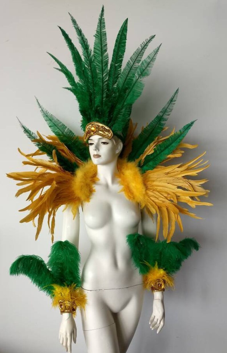 May include: A green and gold feather costume with a headpiece, shoulder pieces, and arm cuffs. The costume is made of feathers and has a gold trim.
