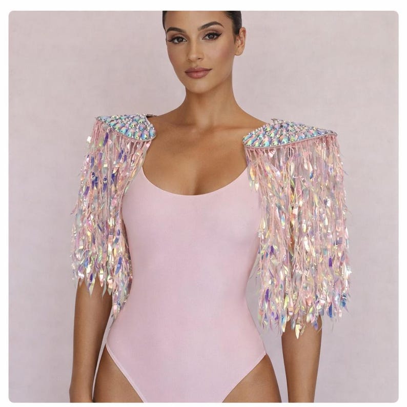 May include: A pair of iridescent shoulder epaulets featuring a dense fringe of shimmering, light-reflecting leaf-shaped sequins attached to a structured base covered in multifaceted, clear, and rainbow-toned crystals that catch the light.