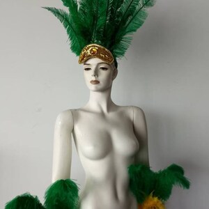 May include: Green feather headdress with gold accents and matching green feather arm cuffs with gold accents.