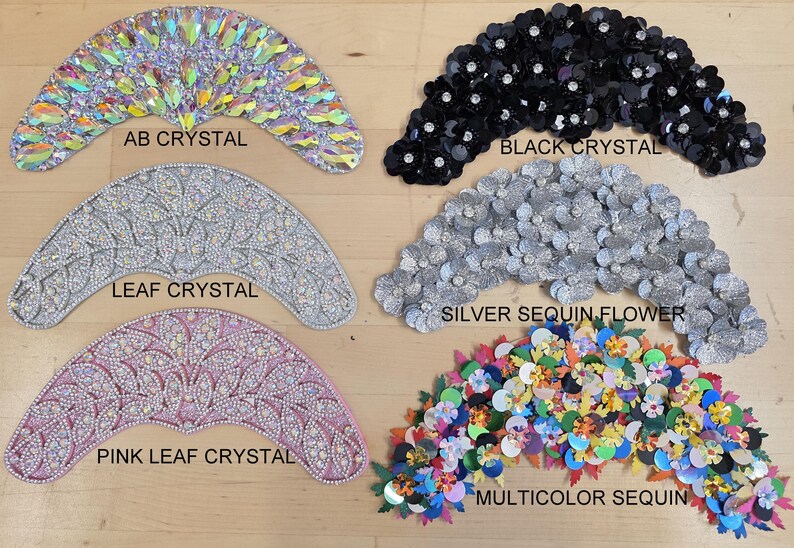 May include: Six crescent-shaped decorative appliques arranged in two columns. The left column features AB crystal, leaf crystal, and pink leaf crystal designs. The right column displays black crystal, silver sequin flower, and multicolor sequin patterns.