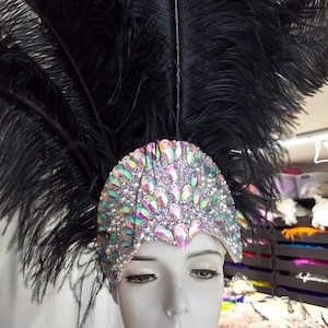 May include: A black feather headdress with iridescent rhinestones. The headdress is worn on a mannequin's head.