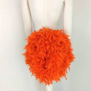 May include: A bright orange feather skirt. The skirt is made of fluffy feathers and is perfect for a costume or party.