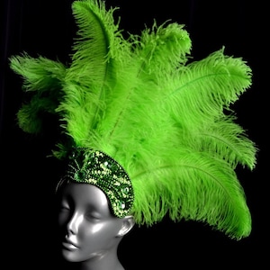 May include: A green feather headdress with a green beaded headband. The headband is decorated with rhinestones.