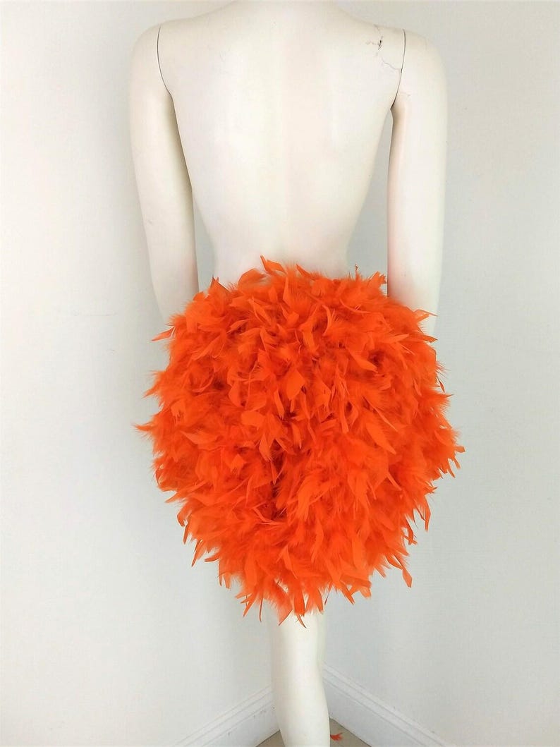 Puede incluir: Una falda de plumas de color naranja brillante. La falda est&aacute; hecha de plumas esponjosas y es perfecta para un disfraz o una fiesta.