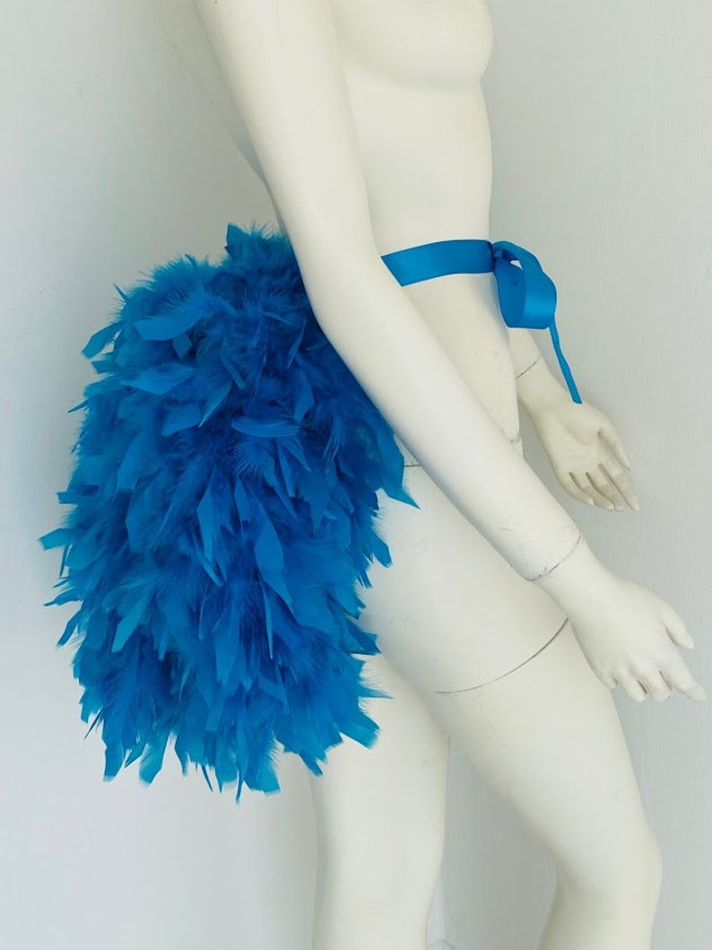 Puede incluir: Un boa de plumas azul brillante atado a la cintura con una cinta azul a juego. El boa es completo y esponjoso, creando un look dram&aacute;tico y llamativo.