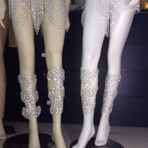 Puede incluir: Dos pares de brazalete de pierna plateados con un dise&ntilde;o de cristal. Los brazaletes est&aacute;n hechos de un material de malla y est&aacute;n adornados con diamantes de imitaci&oacute;n.