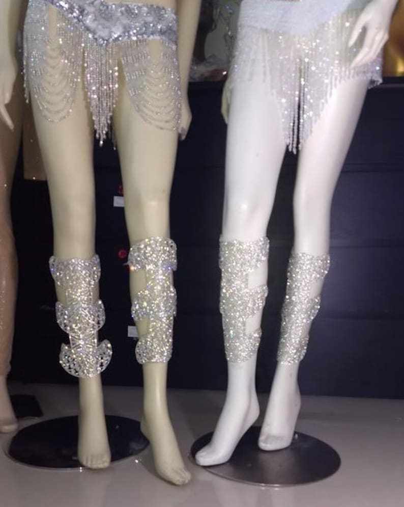 Puede incluir: Dos pares de brazalete de pierna plateados con un dise&ntilde;o de cristal. Los brazaletes est&aacute;n hechos de un material de malla y est&aacute;n adornados con diamantes de imitaci&oacute;n.