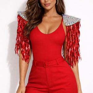 May include: A vibrant red bodysuit paired with matching high-waisted shorts featuring a thin belt. The outfit includes detachable shoulder epaulets adorned with iridescent crystals and long, shimmering red sequin fringe that hangs down the arms.