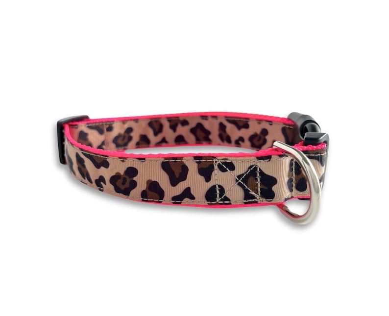 May include: A pink and brown leopard print dog collar with a black buckle and silver D-ring.