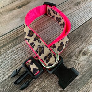 May include: A pink and brown leopard print dog collar with a black plastic buckle.