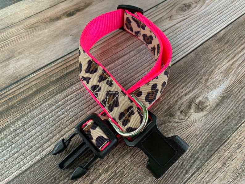 May include: A pink and brown leopard print dog collar with a black plastic buckle.