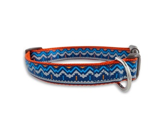 Pode incluir: Uma coleira de cão azul, laranja e cinza com um anel em D prateado e uma fivela de plástico preta.