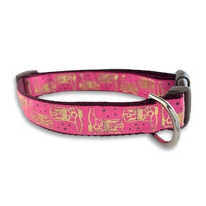 Könnte beinhalten: Rosa Hundekette mit goldfarbenem Aufdruck von Cowboystiefeln. Die Kette hat einen silbernen D-Ring aus Metall.