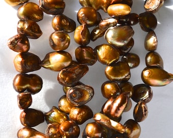 May include: A strand of brown baroque pearls with iridescent highlights. The pearls are irregular in shape and size, creating a unique and natural look.