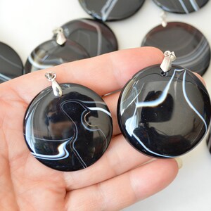 May include: Two black and white agate pendants with silver bail. The pendants are round and have a swirling pattern of white lines on a black background.