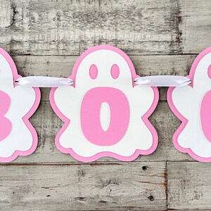 Op de afbeelding: Roze en witte spookbanner met het woord "BOO" erop. Elke letter staat op een apart spook.