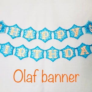 Pu&ograve; includere: Uno striscione blu e bianco di "Buon Compleanno" con ritagli a forma di fiocco di neve. Le lettere sono arancioni e bianche e lo striscione include un'immagine di Olaf. Il testo "Olaf banner" &egrave; scritto in arancione sotto.
