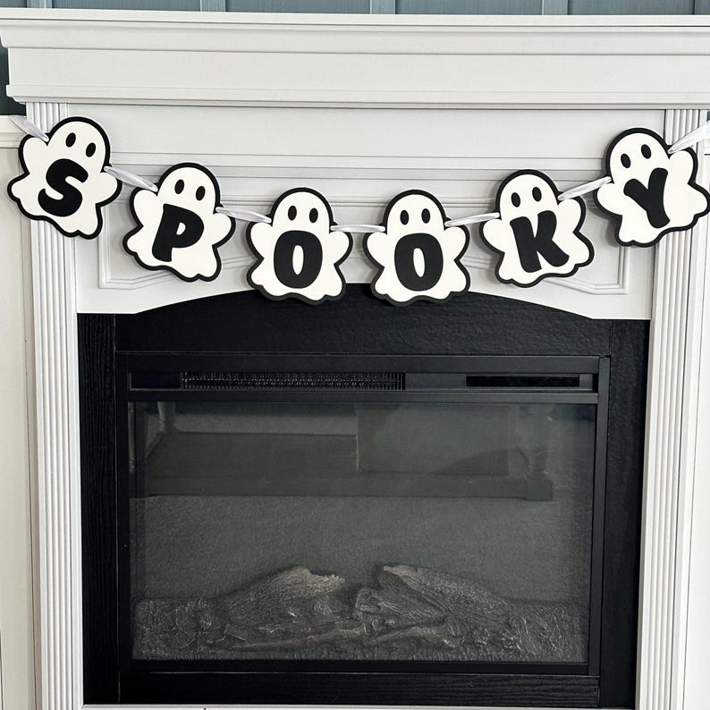 Op de afbeelding: Een zwart-witte spookbanner met het woord "SPOOKY" erop. De banner hangt boven een zwarte open haard.