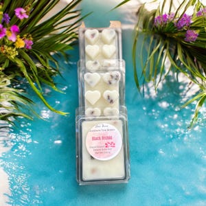 May include: Three packs of heart-shaped wax melts in clear plastic packaging. The wax melts are white with a floral scent and the packaging has a label that reads "Die Vine Illuminate Your Senses Black Orchid Hand Poured Deluxe Satin Soy Net Wt 2.30 oz."