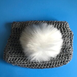 May include: Gray crocheted headband with a white fluffy pom pom.