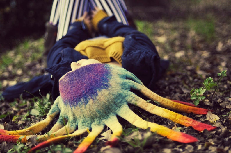 Op de afbeelding: Een kleurrijke, veelkleurige, handgebreide octopusmuts met lange tentakels. De muts is gemaakt van zacht, pluche garen en heeft een uniek, grillig ontwerp.