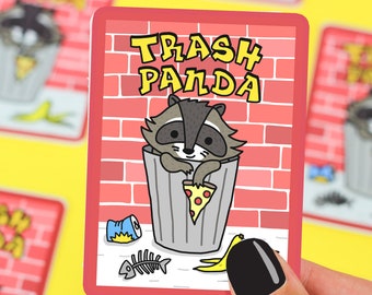 May include: A red card with a cartoon raccoon in a trash can. The raccoon is holding a slice of pizza. The card says "Trash Panda" in graffiti-style lettering. There are other items in the trash can, including a can of soda, a banana peel, and a fish bone.