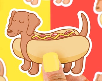 May include: A brown dachshund dog wearing a yellow hot dog costume with mustard and ketchup. The dog is wearing a smile and has its eyes closed. The hot dog costume has the word "Sausage" written on it.
